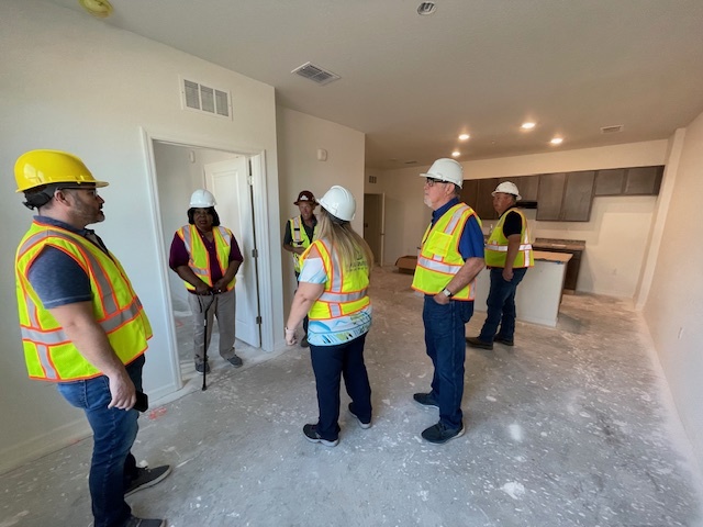 Left to Right - (yellow hard hat) Board Chair Luis Velasco, (in doorway) Board Member Marvella Hearns, (red hard hat) Marmer Construction site foreman Trey Felder, white hard hat - back of Executive Director Becky-Sue Mercer, Board Member Mel Jackson, and NOLLID AHA Asset Risk Manager Frank Dillon.