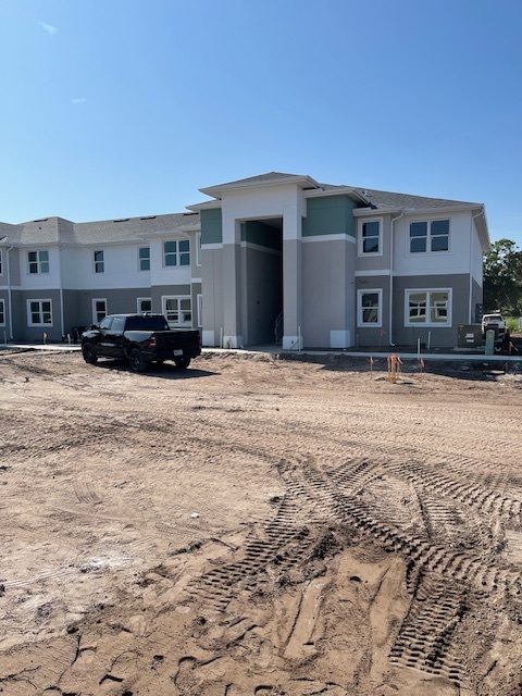 Exterior of the apartment complex with a truck on the dirt ground surrounding it. 