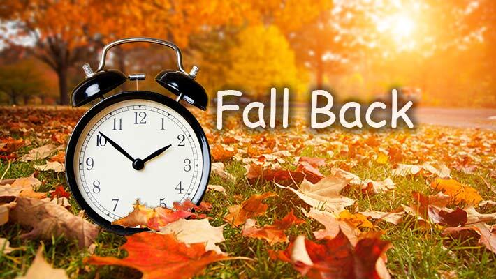 Clock surrounded by leaves with the text, Fall Back. 
