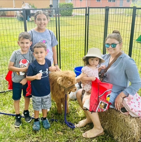 Kids pose with a mini cow.