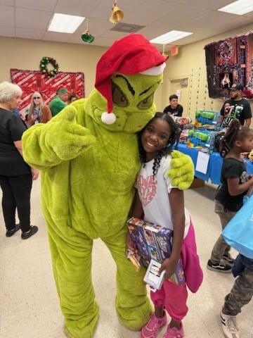 A girl posing with the Grinch for a photo. 