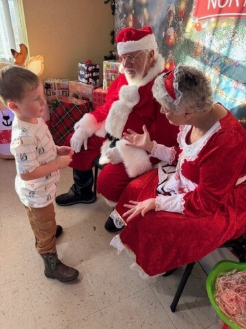 Santa and a young boy listens to Mrs. Claus. 