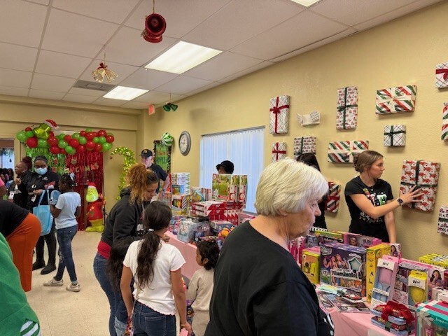 Adults and children are looking at wrapping options with presents on a table. 