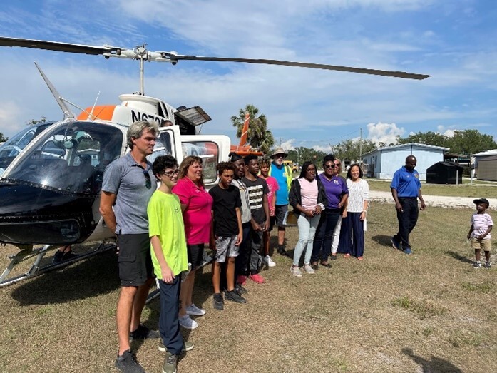 A large group of people posing in front of  helicopter.