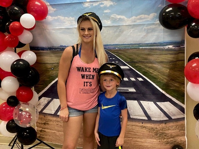 A woman and a boy posing with captains hats.