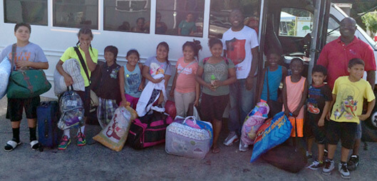Children lining up in front of a bus with their luggage waiting to head to Salvation Army Summer Camp 2019