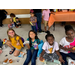 Children with their faces painted having snacks and grinning at the camera.