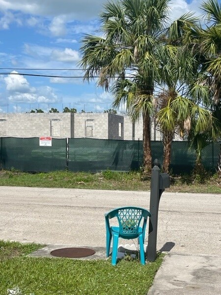 Construction site from across the street with a chair and mailbox next to the road.
