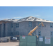 Side of building being worked on with big machine in front.