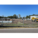 View from across the street of the materials delivered to the construction site with some machines and a trailer.