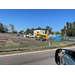 View from across the street of the vehicles on the construction site and a port-a-potty.