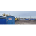 Construction equipment and building materials behind a port-a-potty.