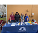 Four women standing behind a Step Up Suncoast booth table with merchandise on it. 