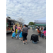 A food truck with people walking along a row of tradeshow tents. 