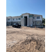 External photo of the apartment complex with a black truck on the dirt ground. 