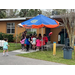 Multiple people gather under an umbrella.