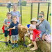 A group of kids pose with a mini cow.
