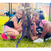 Two girls cuddle a mini cow.