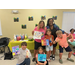 A group of children and two adults pose with paintings.