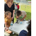  A woman standing by two kids who are looking in a telescope. 