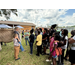  A woman standing by a cow talking to a group of kids. 