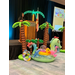  A woman speaking at a podium on a stage with palm tree inflatables and various other inflatables in front of it. 