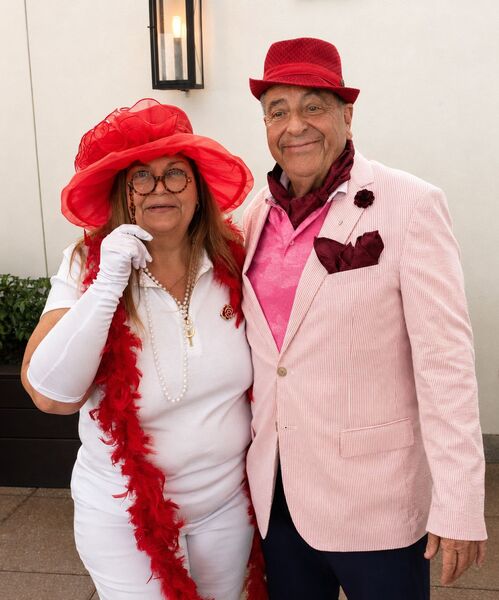 Becky-Sue dressed up with a hat and glasses next to a man in a hat, smiling for a photo.