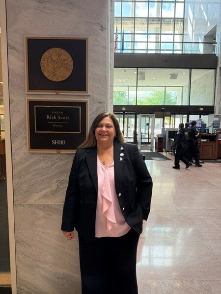 Arcadia Housing Authority Executive Director, Becky-Sue Mercer, standing next to a name plaque for Senator Rick Scott.